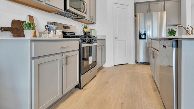 194 Inks Ln, Kyle, TX 78640 - kitchen with appliances with stainless steel finishes, gray cabinets, light wood finished floors, and light countertops