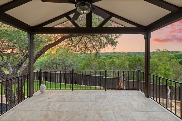 patio terrace at dusk featuring a view of trees