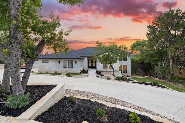 view of front of property featuring stone siding and roof with shingles