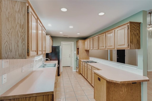 kitchen with stainless steel oven, light brown cabinets, light countertops, a peninsula, and a sink