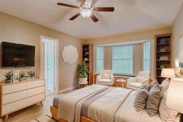 bedroom featuring light wood-style flooring, a ceiling fan, and baseboards