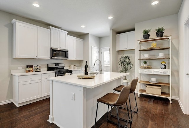 532 Emory Crossing Blvd, Hutto, TX 78634 - kitchen with gas range oven, stainless steel microwave, a sink, white cabinets, and dark wood finished floors