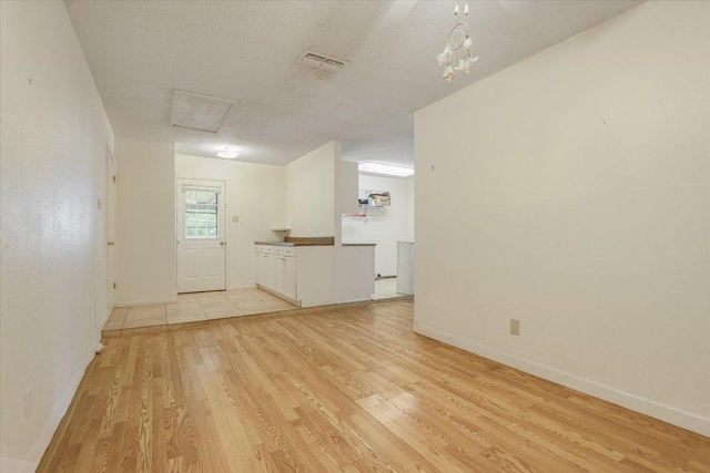 spare room with light wood-style floors, baseboards, and attic access