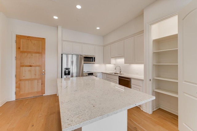 102 Bella Toscana Ave Unit 1306, Lakeway, TX 78734 - kitchen featuring stainless steel appliances, a sink, light wood-style flooring, light stone counters, and white cabinetry