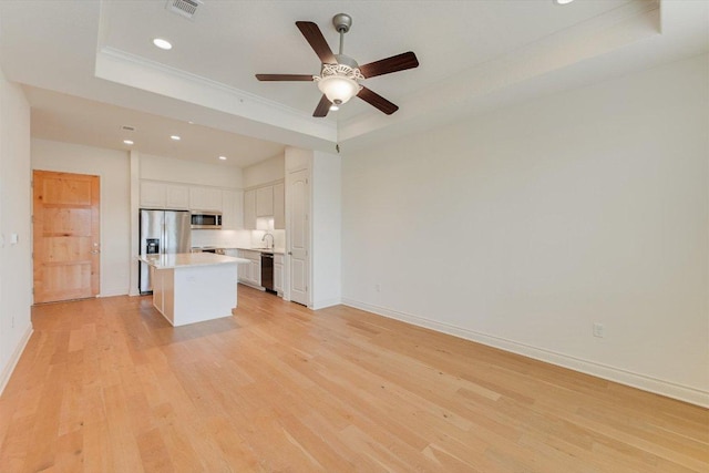 102 Bella Toscana Ave Unit 1306, Lakeway, TX 78734 - unfurnished living room with a raised ceiling, recessed lighting, light wood-style flooring, baseboards, and a sink