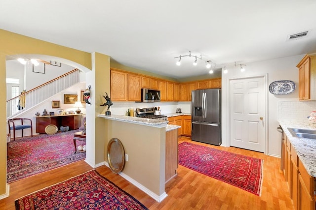 2111 Marcus Abrams Blvd, Austin, TX 78748 - kitchen with stainless steel appliances, light wood-style floors, a sink, tasteful backsplash, and a peninsula