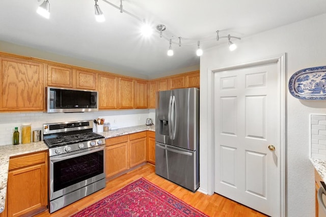 2111 Marcus Abrams Blvd, Austin, TX 78748 - kitchen with stainless steel appliances, light wood-style floors, backsplash, and light stone countertops