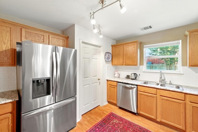 2111 Marcus Abrams Blvd, Austin, TX 78748 - kitchen featuring stainless steel appliances, a sink, light wood-style flooring, decorative backsplash, and light stone countertops