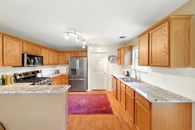 2111 Marcus Abrams Blvd, Austin, TX 78748 - kitchen featuring appliances with stainless steel finishes, light wood finished floors, a sink, and backsplash