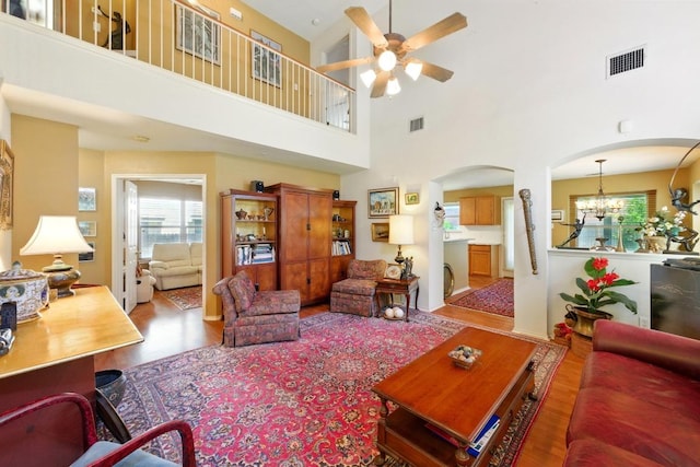 2111 Marcus Abrams Blvd, Austin, TX 78748 - living room featuring arched walkways, wood finished floors, ceiling fan, a chandelier, and a high ceiling