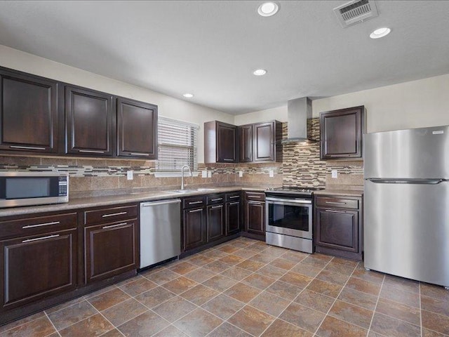 200 Karrie Dr, Kyle, TX 78640 - kitchen featuring appliances with stainless steel finishes, wall chimney exhaust hood, tasteful backsplash, dark brown cabinetry, and recessed lighting
