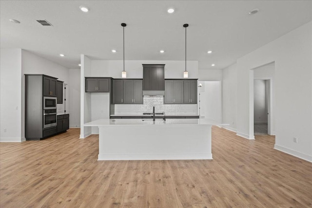 145 Lost Tree Dr, Buda, TX 78610 - kitchen featuring stainless steel appliances, a kitchen island with sink, decorative backsplash, baseboards, and light countertops