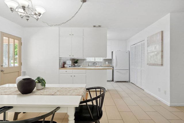 1409 Briarcliff Blvd, Austin, TX 78723 - kitchen featuring white appliances, light countertops, a chandelier, tasteful backsplash, and baseboards
