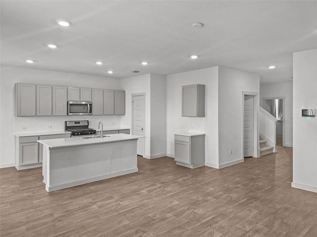 kitchen featuring appliances with stainless steel finishes, gray cabinets, baseboards, light wood-style flooring, and recessed lighting