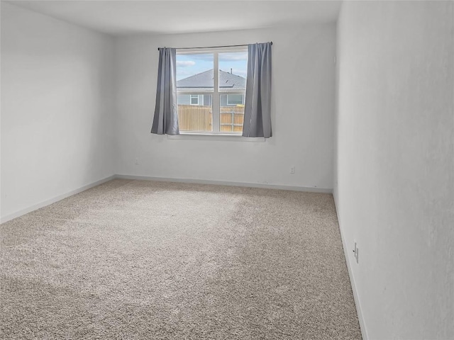 spare room featuring carpet floors and baseboards