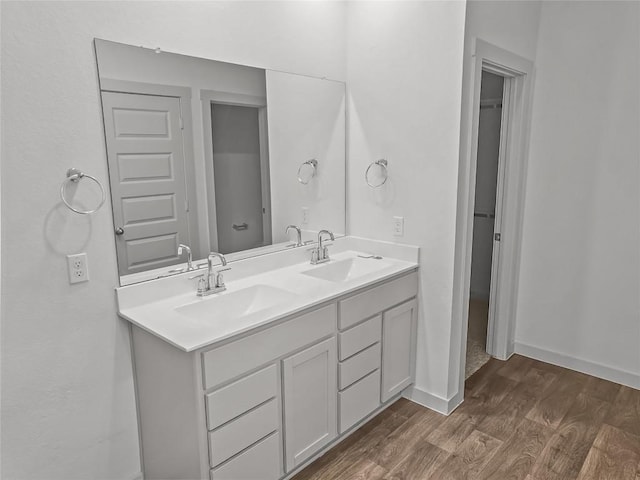 bathroom with wood finished floors, double vanity, and baseboards