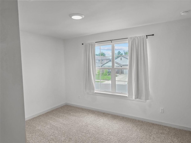 carpeted empty room featuring baseboards