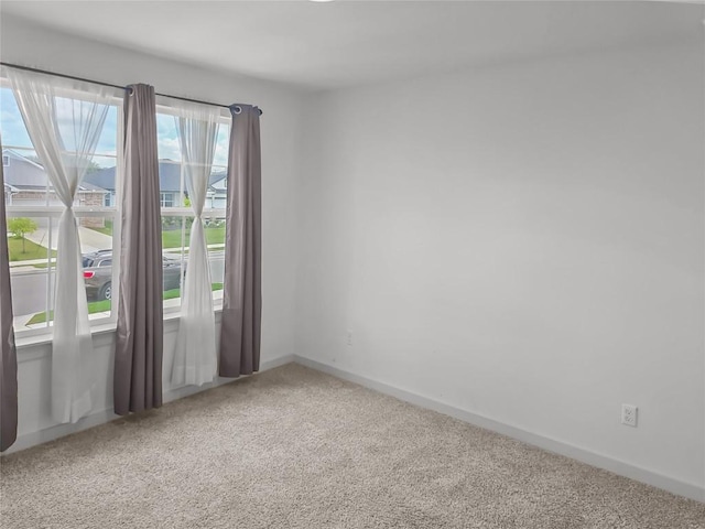 carpeted empty room featuring baseboards