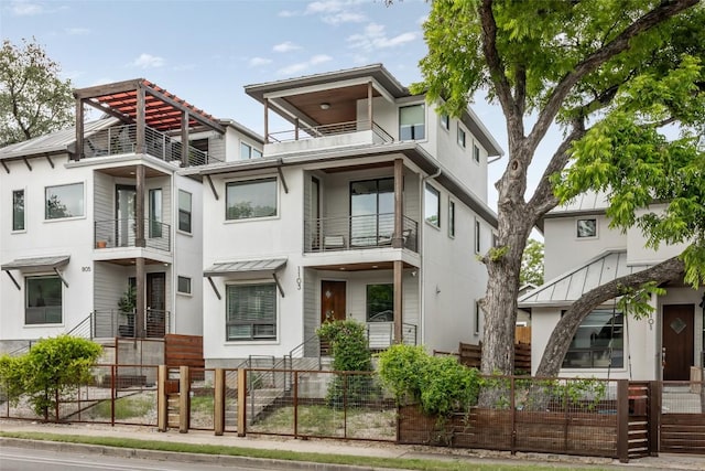 1103 12th St E, Austin, TX 78702 - view of front facade featuring a balcony, stucco siding, a fenced front yard, and a gate