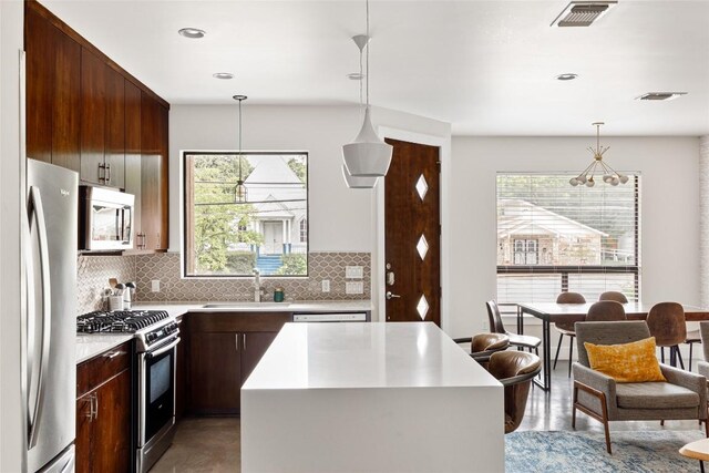 1103 12th St E, Austin, TX 78702 - kitchen featuring appliances with stainless steel finishes, a sink, light countertops, backsplash, and decorative light fixtures