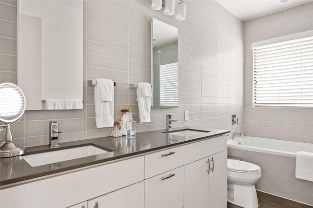 1103 12th St E, Austin, TX 78702 - bathroom with tile walls, toilet, tiled tub, backsplash, and double vanity