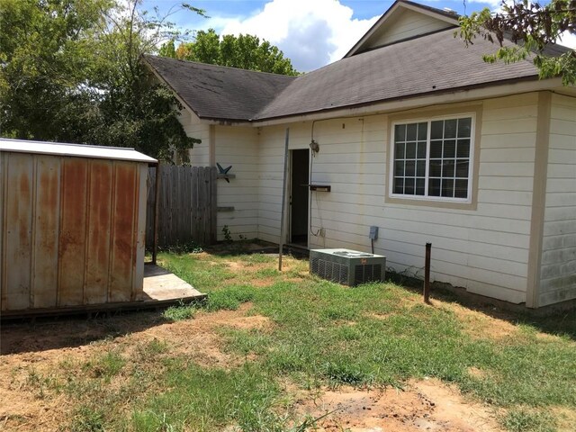 251 Zimmerman Ave A-B-C-D, Unit A-B-C-D, Bastrop, TX 78602 - back of property featuring cooling unit, a shingled roof, an outdoor structure, and a shed