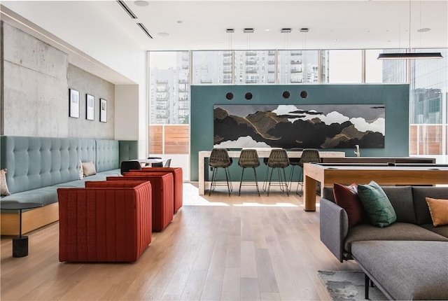 rec room featuring wood finished floors, floor to ceiling windows, and healthy amount of natural light