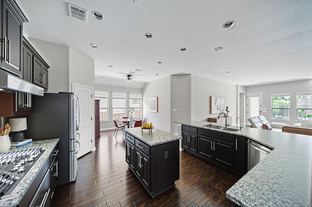 4121 Vinalopo Dr, Austin, TX 78738 - kitchen with a kitchen island, stainless steel appliances, dark cabinets, under cabinet range hood, and open floor plan
