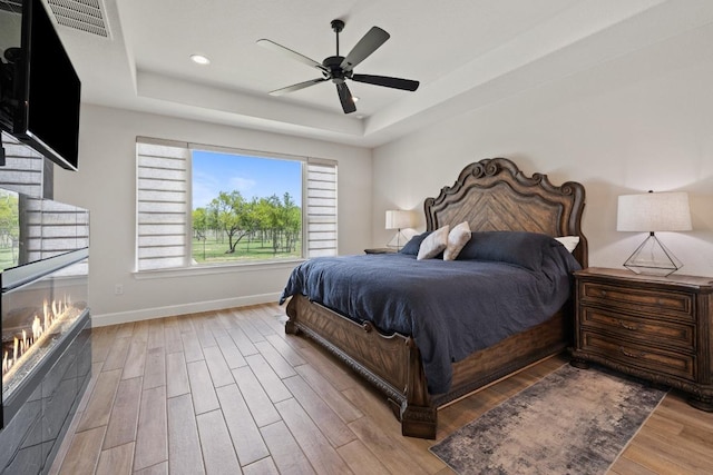 10900 Ranch Road 1323, Johnson City, TX 78636 - bedroom featuring wood finished floors, a raised ceiling, baseboards, recessed lighting, and a ceiling fan