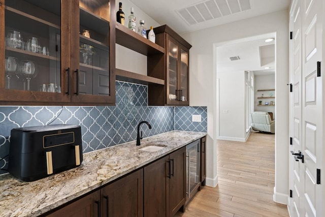 10900 Ranch Road 1323, Johnson City, TX 78636 - kitchen with dark brown cabinetry, a sink, light wood finished floors, backsplash, and baseboards