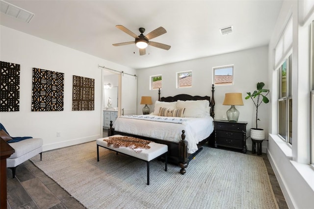 417 Wichita St, Meadowlakes, TX 78654 - bedroom with a barn door, wood finished floors, baseboards, ensuite bathroom, and ceiling fan