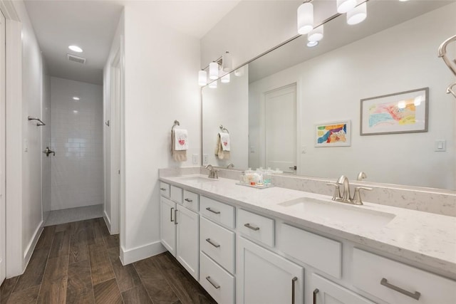 417 Wichita St, Meadowlakes, TX 78654 - bathroom with double vanity, wood finished floors, tiled shower, and baseboards