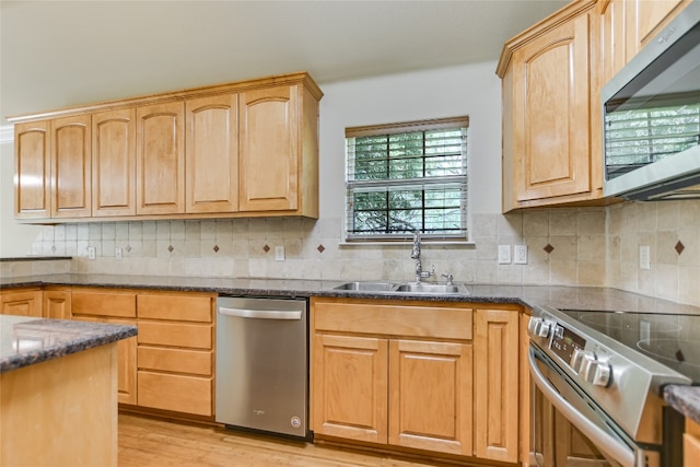 104 Springfield, Horseshoe Bay, TX 78657 - kitchen with appliances with stainless steel finishes, a sink, light wood-style floors, tasteful backsplash, and dark stone counters