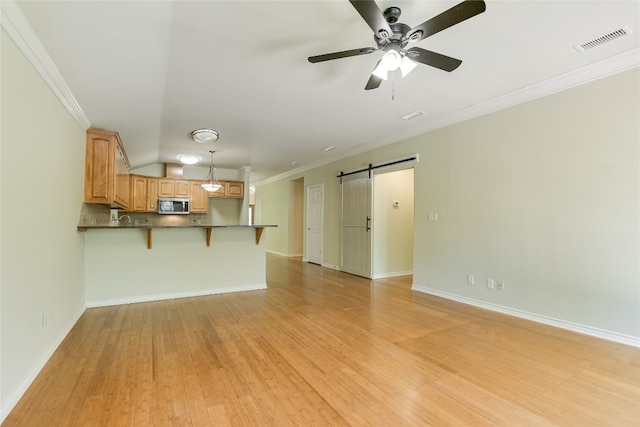 104 Springfield, Horseshoe Bay, TX 78657 - unfurnished living room featuring a barn door, light wood-style floors, crown molding, a ceiling fan, and baseboards