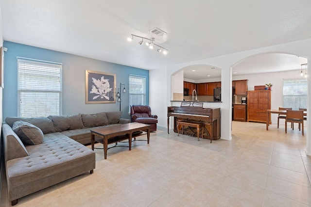 living area featuring arched walkways, plenty of natural light, and light tile patterned flooring