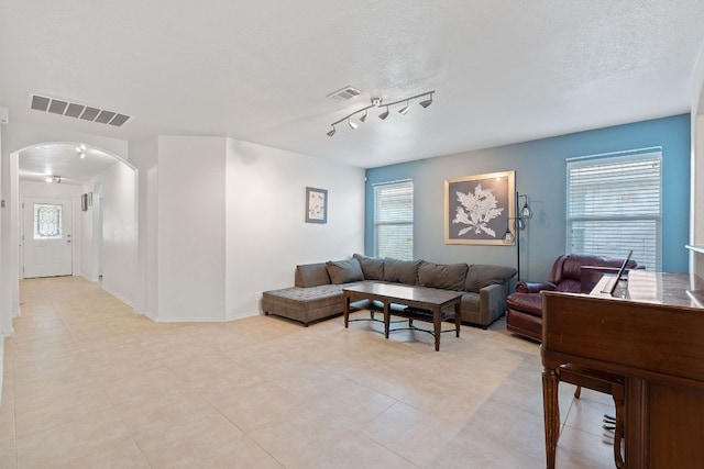 living area with arched walkways, a textured ceiling, and baseboards