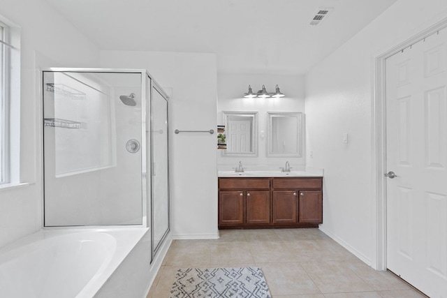 bathroom with a garden tub, tile patterned floors, a stall shower, baseboards, and double vanity