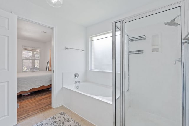 ensuite bathroom with tile patterned floors, a stall shower, and a bath