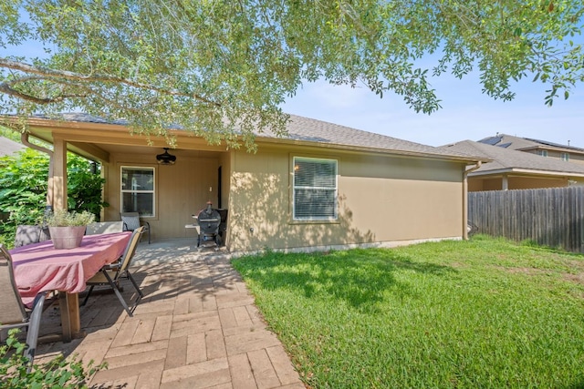 rear view of property with a patio, a ceiling fan, and roof with shingles