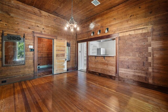 1019 W 4th St, Taylor, TX 76574 - empty room with wood walls, a chandelier, hardwood / wood-style floors, and wood ceiling