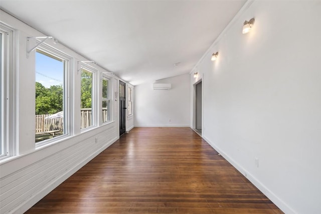 1019 W 4th St, Taylor, TX 76574 - unfurnished room with an AC wall unit, vaulted ceiling, dark wood-style floors, and baseboards