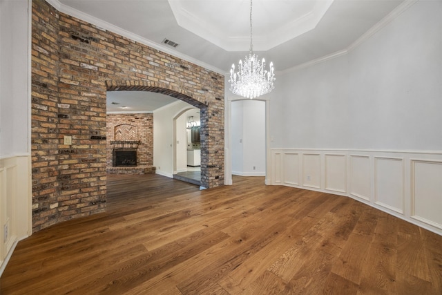 10242 Pinehurst Dr, Austin, TX 78747 - unfurnished dining area with a raised ceiling, a chandelier, wood finished floors, arched walkways, and a brick fireplace