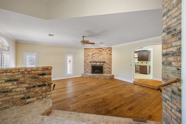 10242 Pinehurst Dr, Austin, TX 78747 - unfurnished living room with crown molding, ceiling fan, light wood-type flooring, a fireplace, and arched walkways