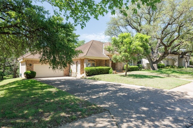 10242 Pinehurst Dr, Austin, TX 78747 - obstructed view of property with asphalt driveway, an attached garage, brick siding, a front yard, and a tiled roof