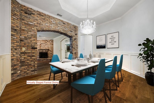 10242 Pinehurst Dr, Austin, TX 78747 - dining room with a tray ceiling, a chandelier, wood finished floors, arched walkways, and a brick fireplace