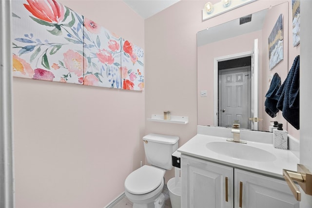 bathroom with toilet, vanity, and baseboards