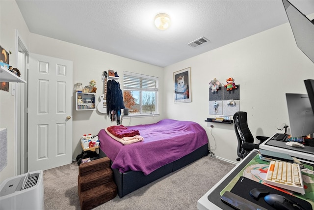bedroom with carpet, a textured ceiling, and a desk