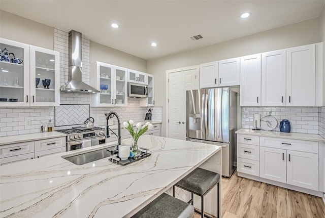 171 Eely Rd, Mcdade, TX 78650 - kitchen featuring appliances with stainless steel finishes, wall chimney exhaust hood, backsplash, light stone countertops, and recessed lighting