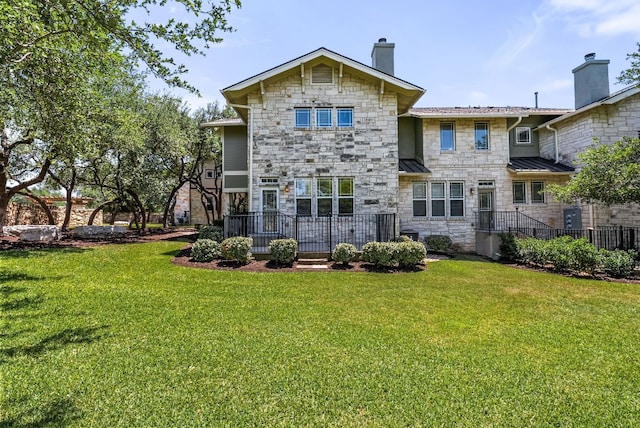 2930 Grand Oaks Loop Unit 401, Cedar Park, TX 78613 - rear view of property with stone siding, a chimney, a lawn, and a standing seam roof
