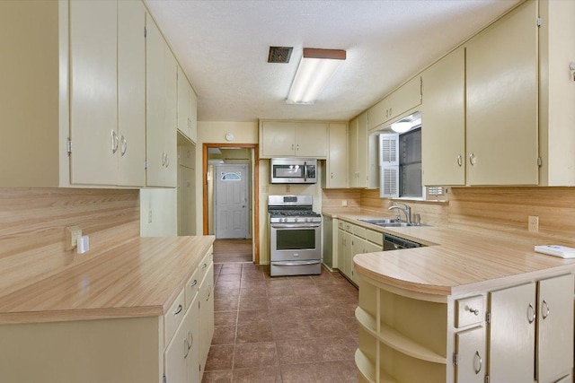 6009 Belfast Dr, Austin, TX 78723 - kitchen featuring stainless steel appliances, light countertops, a sink, a peninsula, and open shelves